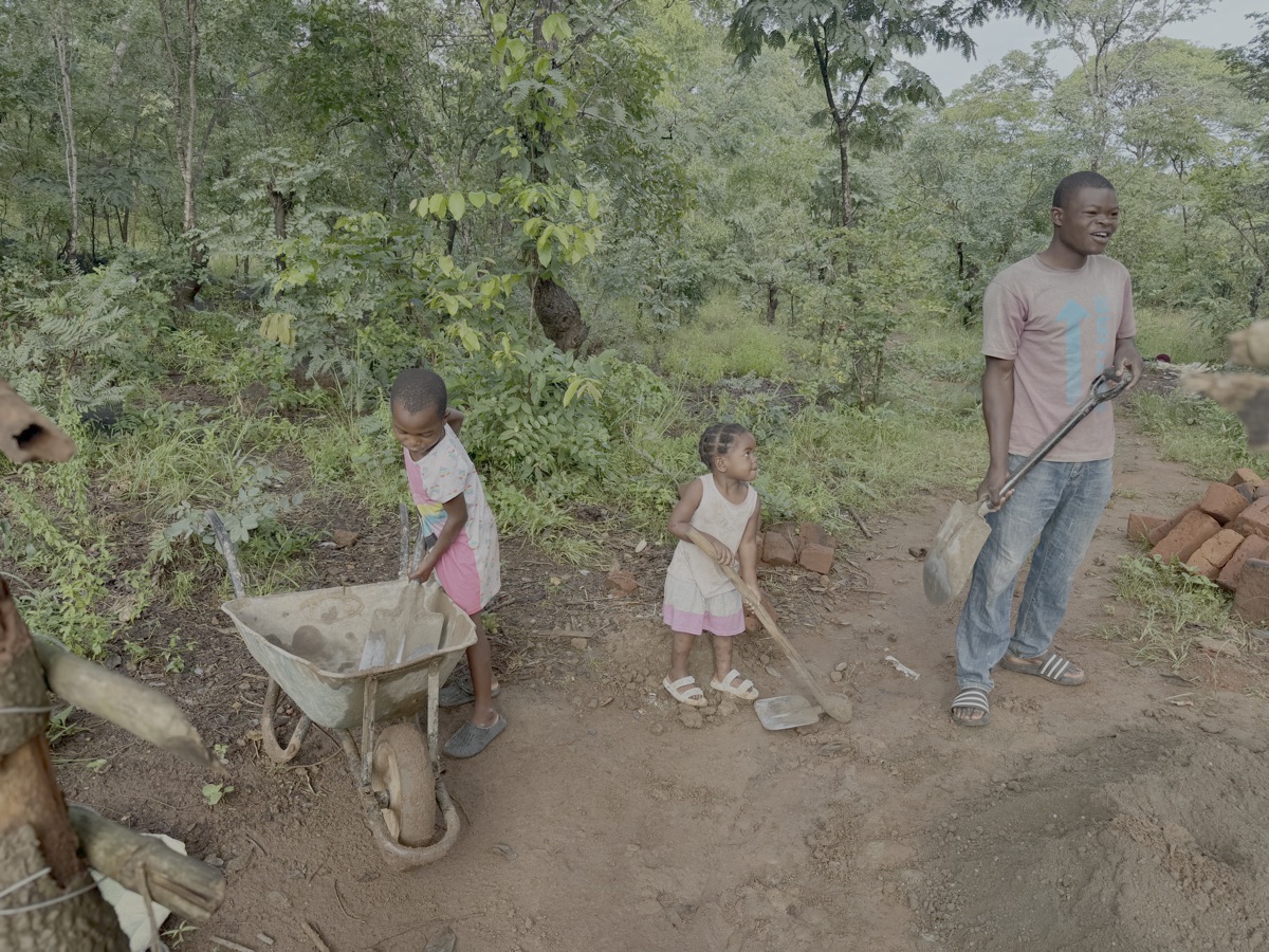 14-02-2026: Het werk aan de kippenschuur gaat door. Janet (links) en Joanna helpen een handje. Rechts op de foto Solomon.