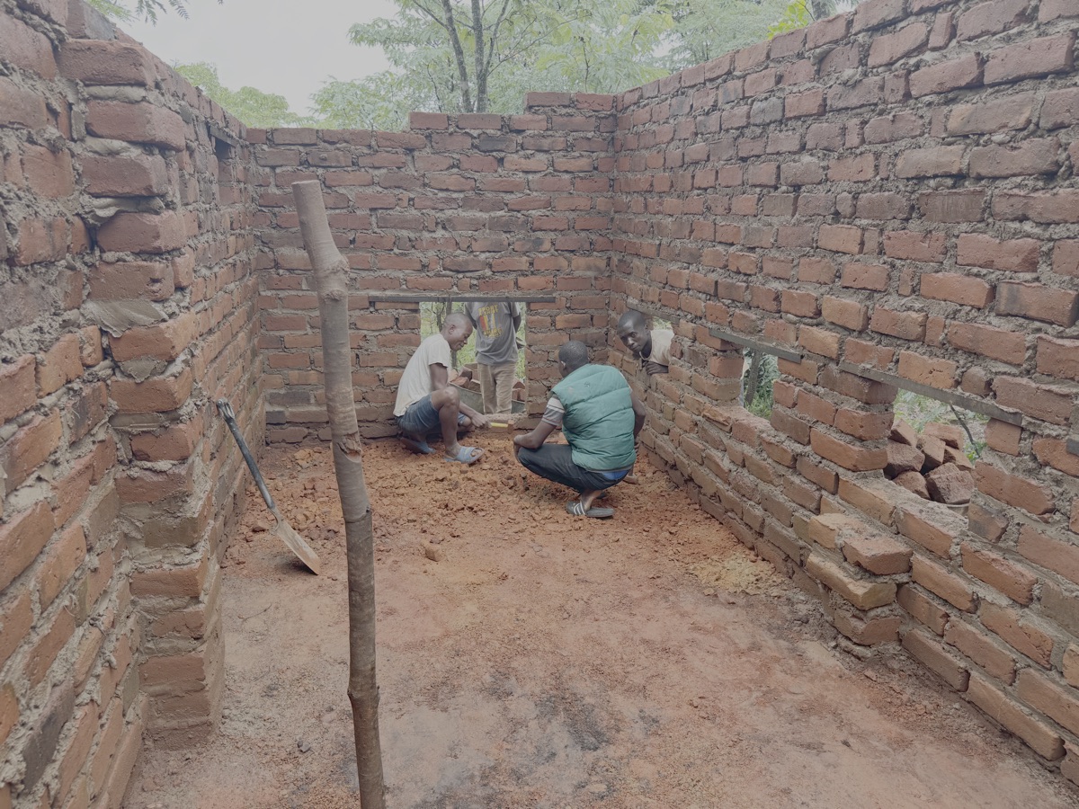 18-02-2026: De binnenkant van de kippenschuur wordt opgevuld met geplette baksteen. Daarna wordt er een betonnen vloer gemaakt. De kippen lopen op een dikke laag pinda doppen, die samen met de mest door de opening aan het eind worden verwijderd. Daar bevindt zich ook de composthoop dus alles ligt mooi dicht bij elkaar