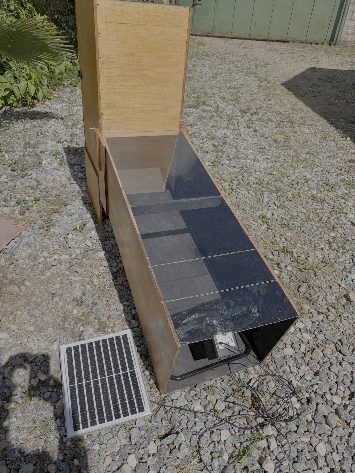 De ventilator is hier in de matzwart geverfde koker geplaatst en duwt de verwarmde lucht door de bakken met in reepjes gesneden mango's